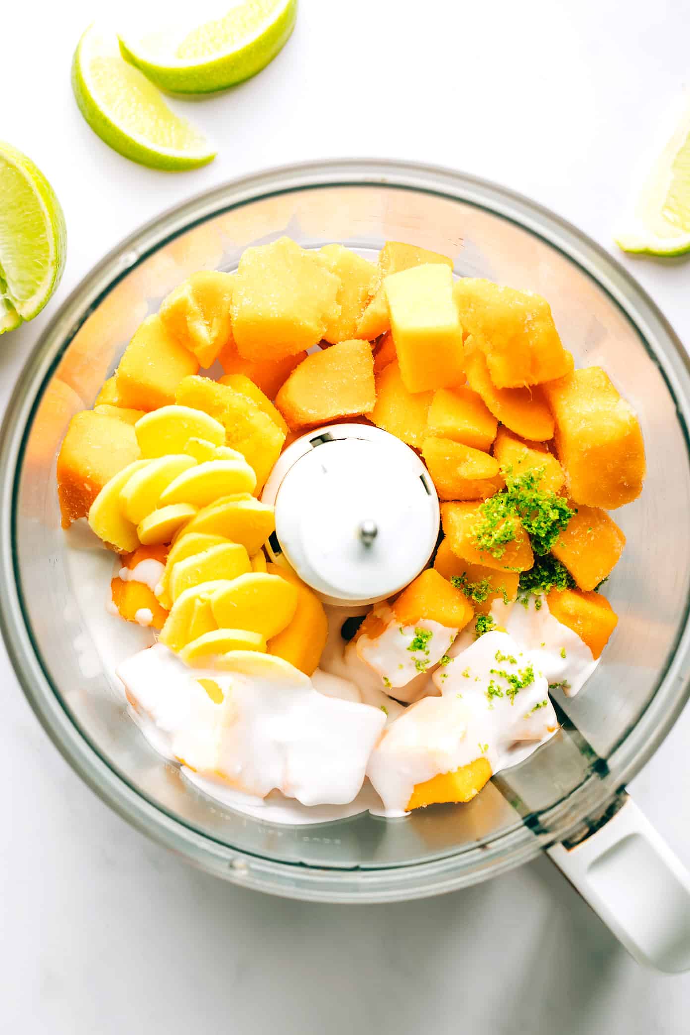 This 5-minute mango lime sorbet is easy to make in a food processor or blender, and made with a delicious blend of mango, lime, coconut milk and fresh ginger. It's the perfect refreshing dessert for summer entertaining, and naturally gluten-free, dairy-free, vegetarian and vegan. | gimmesomeoven.com Mango Lime Sorbet Ingredients in Food Processor