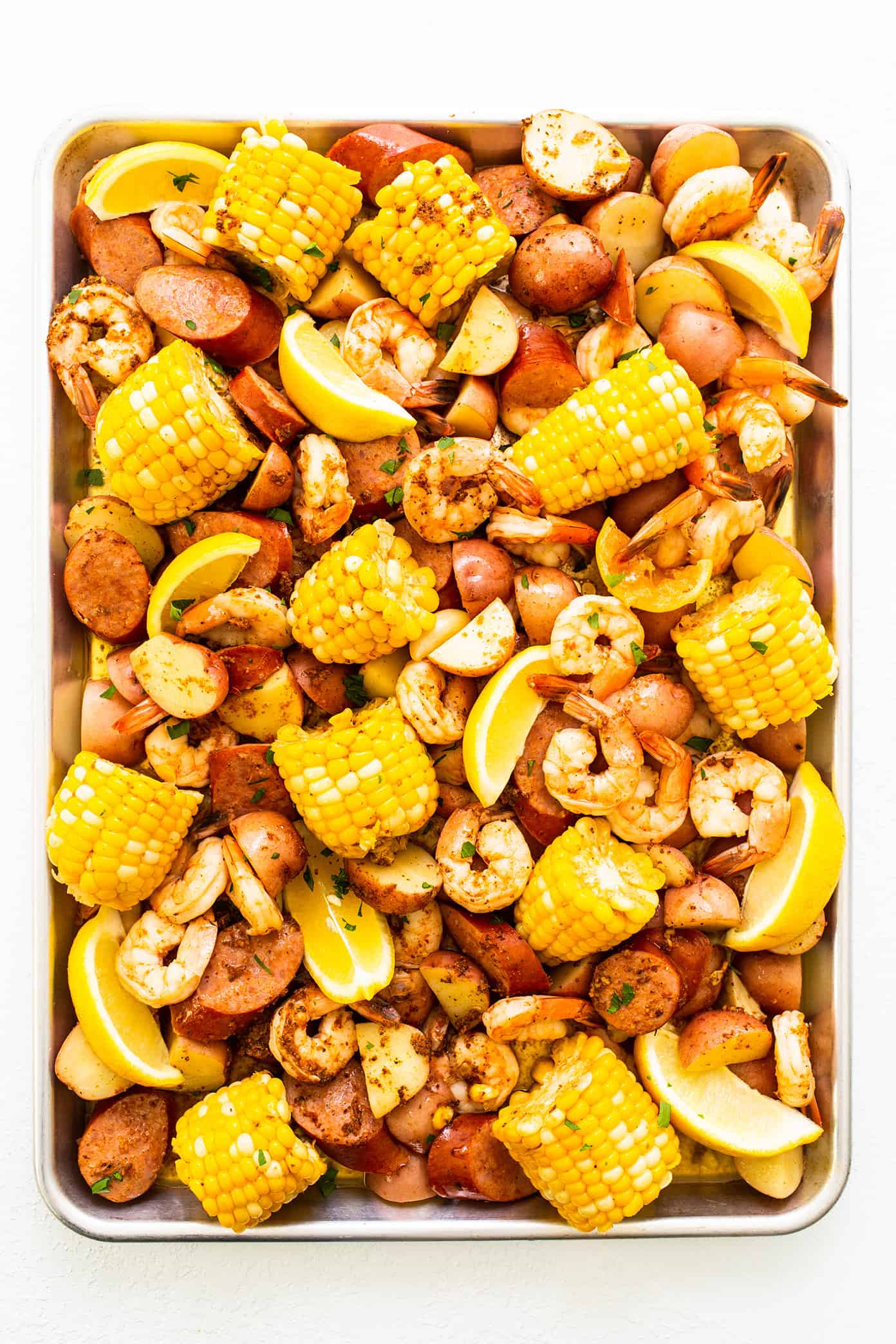 This classic shrimp boil recipe is super-easy to make with tender shrimp, sausage, potatoes, corn, zesty seasonings and a dreamy lemon garlic brown butter sauce. It's the perfect meal for easy entertaining and always a crowd fave! | gimmesomeoven.com Shrimp Boil on Sheet Pan