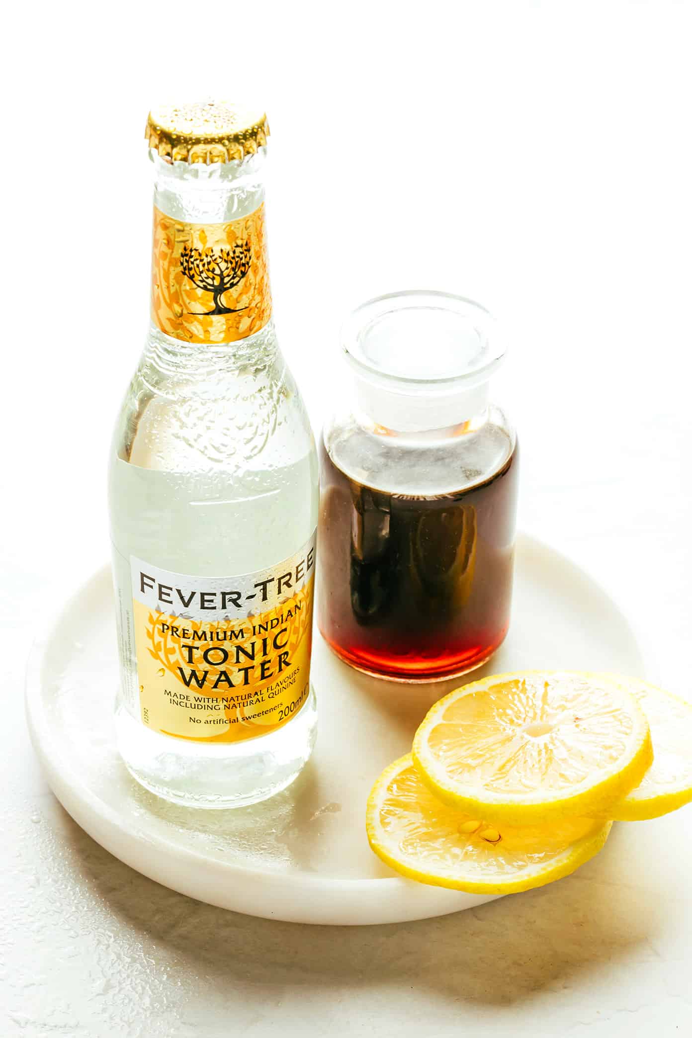 This cold brew tonic recipe is easy to make in a few minutes with three ingredients (cold brew coffee concentrate, tonic water, slice of lemon or orange, plus ice). Always such a refreshing, fizzy and delicious drink! | gimmesomeoven.com Cold Brew Tonic Ingredients on Plate