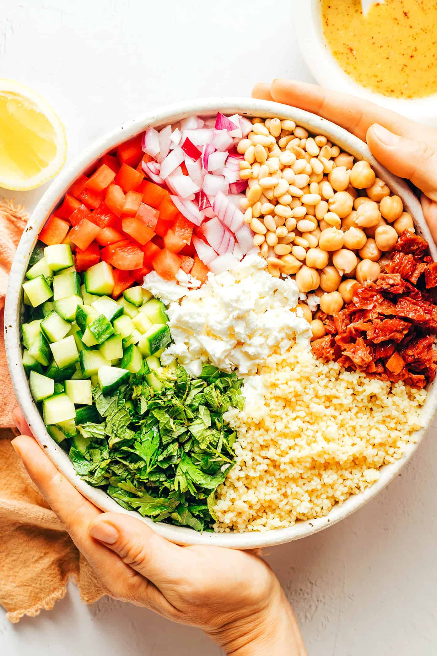 This simple couscous salad is made with loads of fresh veggies (cucumber, bell pepper, red onion), chickpeas, fresh mint and parsley, feta cheese, toasted pine nuts, and a zesty lemon dressing. Feel free to add in some chicken, salmon or shrimp in there too if you'd like. It's the perfect vegetarian entree or side salad...and tastes great for leftovers the next day! | gimmesomeoven.com Couscous Salad Ingredients in Bowl