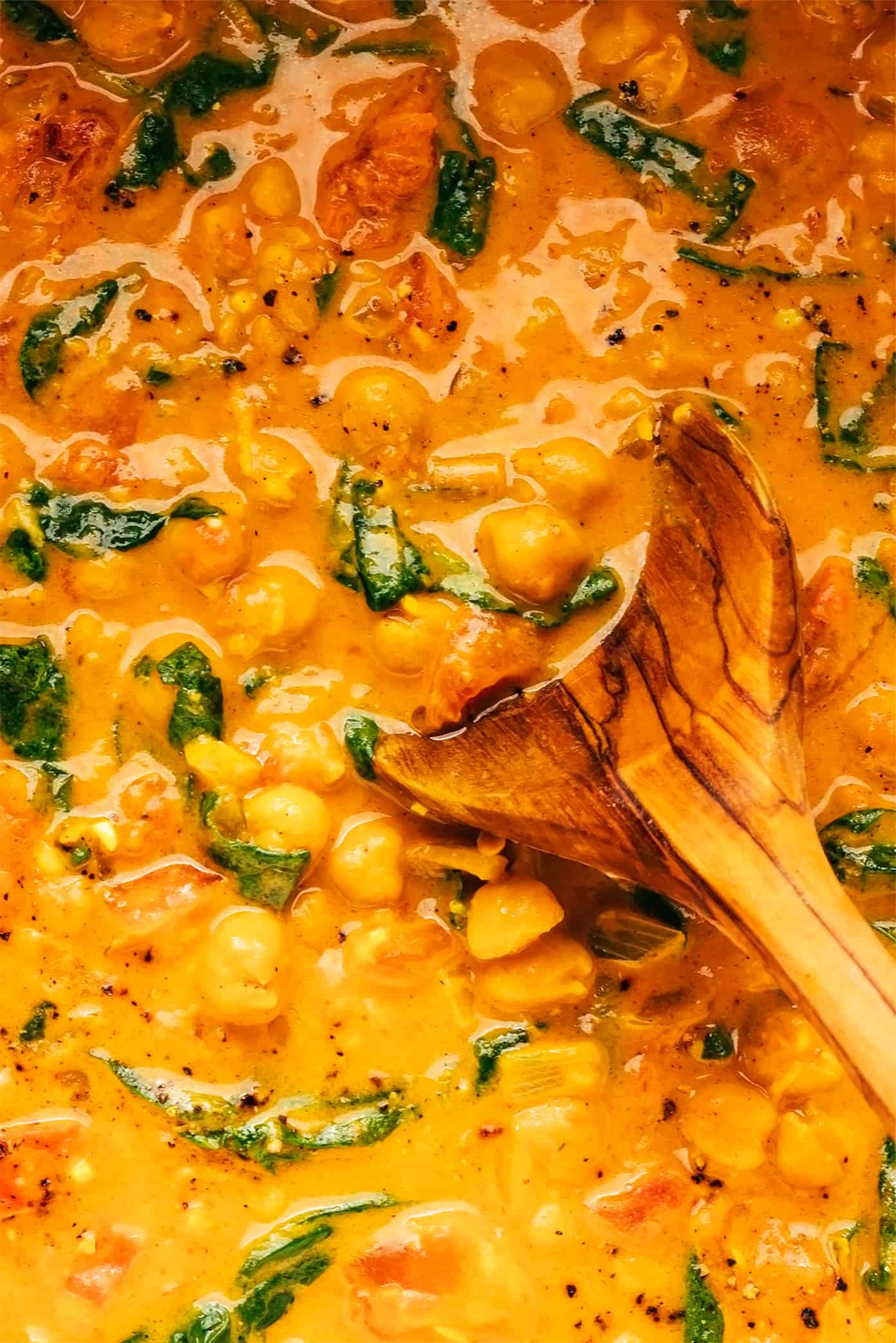 This Indian-inspired chickpea curry recipe is incredibly easy to make in less than 30 minutes and simmered in the most delicious lemon-ginger coconut curry sauce. Naturally gluten-free, vegetarian and vegan! | gimmesomeoven.com Chickpea Curry Closeup with Wooden Spoon