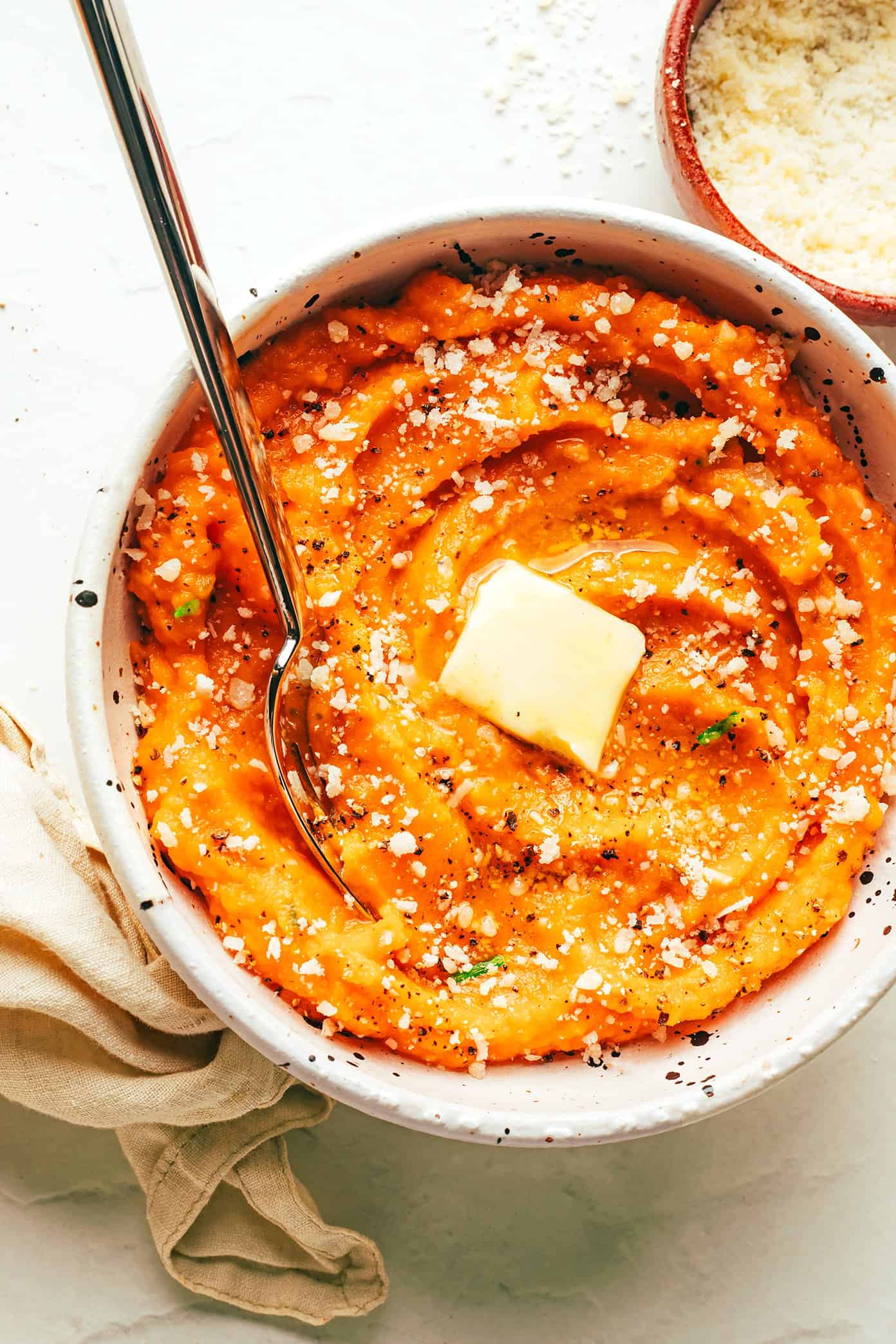 This Garlic Parmesan Mashed Sweet Potatoes recipe is easy to make, irresistibly sweet and savory, and sooo good. They're the perfect side dish for Thanksgiving or anytime you're craving some sweet potatoes! (Vegetarian + Gluten-Free) | gimmesomeoven.com Garlic Parmesan Mashed Sweet Potatoes with Butter in Bowl