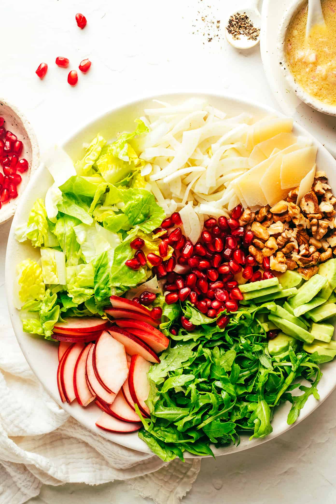 My favorite holiday green salad is tossed with arugula, pomegranate, apple, fennel, toasted walnuts, Parmesan and a simple shallot vinaigrette. Perfect for Thanksgiving, Christmas, or any winter weeknight that you're craving a fresh and delicious salad. | gimmesomeoven.com Holiday Green Salad Ingredients (pomegranate, apple, arugula, avocado, walnuts, Parmesan, fennel, lettuce, shallot vinaigrette)