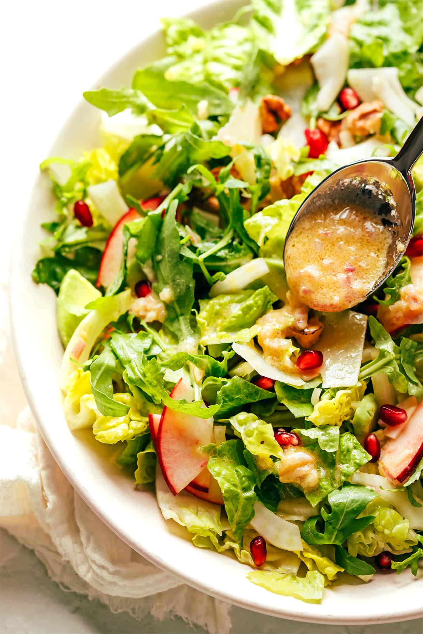My favorite holiday green salad is tossed with arugula, pomegranate, apple, fennel, toasted walnuts, Parmesan and a simple shallot vinaigrette. Perfect for Thanksgiving, Christmas, or any winter weeknight that you're craving a fresh and delicious salad. | gimmesomeoven.com Adding shallot vinaigrette to pomegranate salad