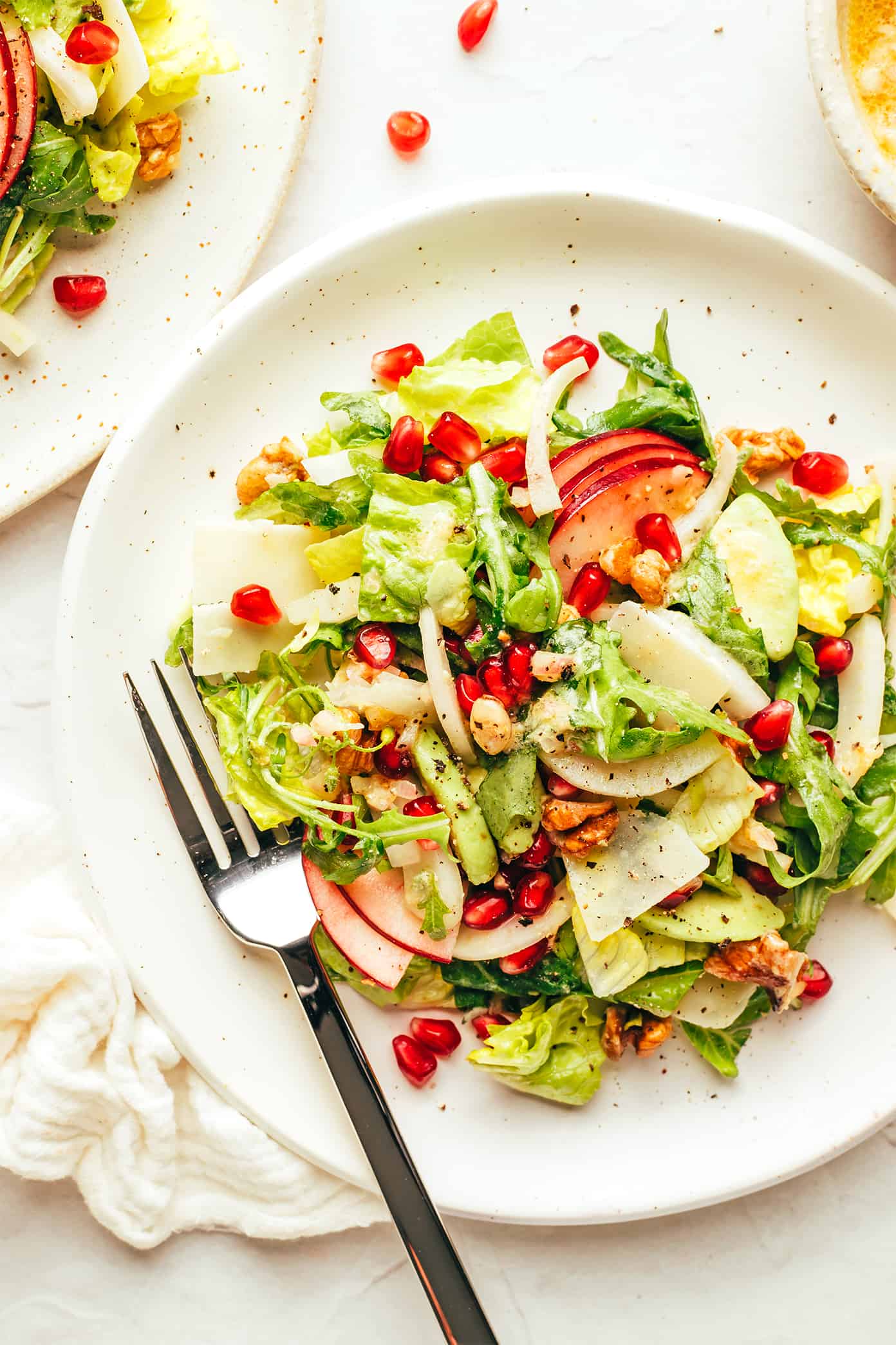 My favorite holiday green salad is tossed with arugula, pomegranate, apple, fennel, toasted walnuts, Parmesan and a simple shallot vinaigrette. Perfect for Thanksgiving, Christmas, or any winter weeknight that you're craving a fresh and delicious salad. | gimmesomeoven.com Christmas Salad on plate (with apple, pomegranate, Parmesan and walnuts)