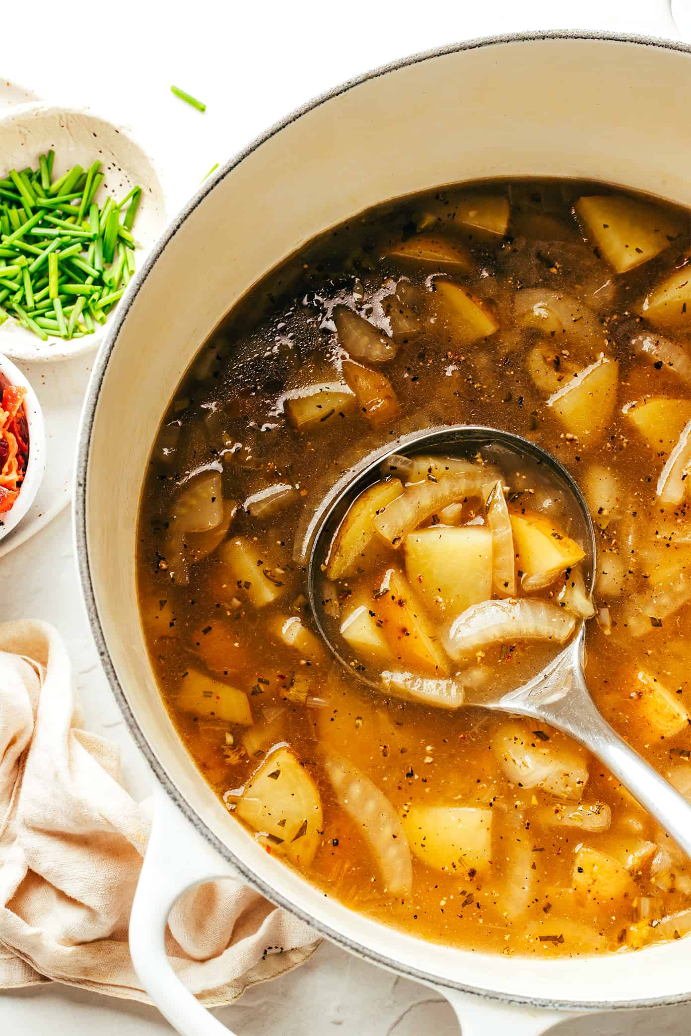 This potato bacon fennel soup recipe is incredibly easy to make and simmered in a garlic-rosemary broth. Easy to make, naturally gluten-free, and always such a cozy and delicious dinner recipe! | gimmesomeoven.com Potato Bacon Fennel Soup in Stockpot with Ladle