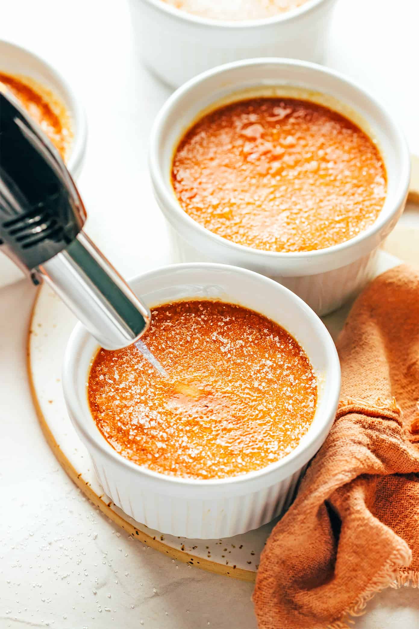 This salted caramel crème brûlée recipe is easy to make with 5 basic ingredients and features a delicious salted caramel custard with a crispy, crackly sugar topping. A delicious dessert that's easy for entertaining and also happens to be gluten-free. | gimmesomeoven.com Using a kitchen torch to caramelize the sugar for Crème Brûlée