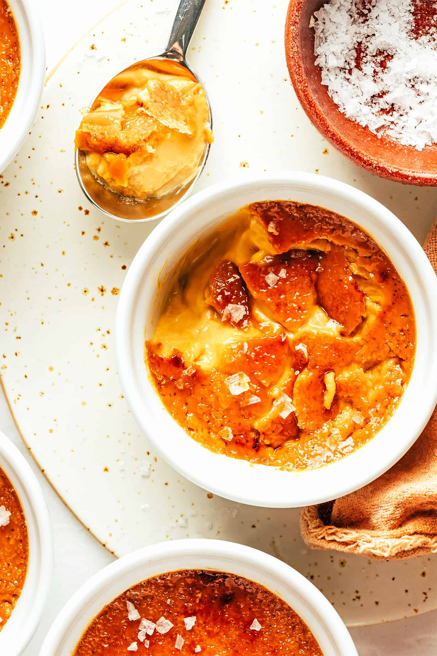 This salted caramel crème brûlée recipe is easy to make with 5 basic ingredients and features a delicious salted caramel custard with a crispy, crackly sugar topping. A delicious dessert that's easy for entertaining and also happens to be gluten-free. | gimmesomeoven.com Salted Caramel Crème Brûlée with Spoon Bite