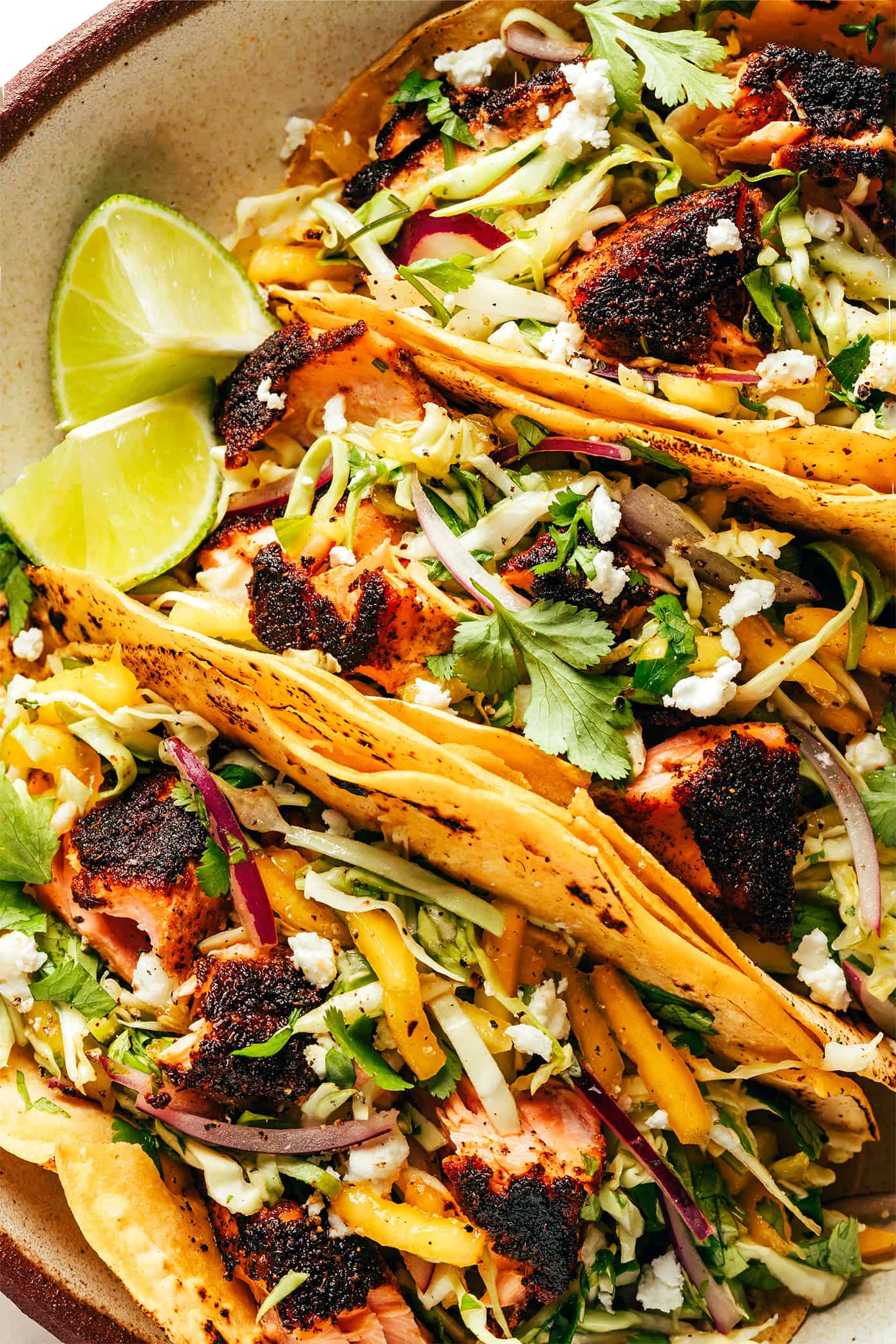 This blackened salmon tacos recipe is layered with a quick mango slaw, corn tortillas, and your choice of zesty toppings. Quick and easy to prepare, naturally gluten-free, and always such a delicious and healthy dinner recipe! | gimmesomeoven.com Blackened Fish Tacos Closeup