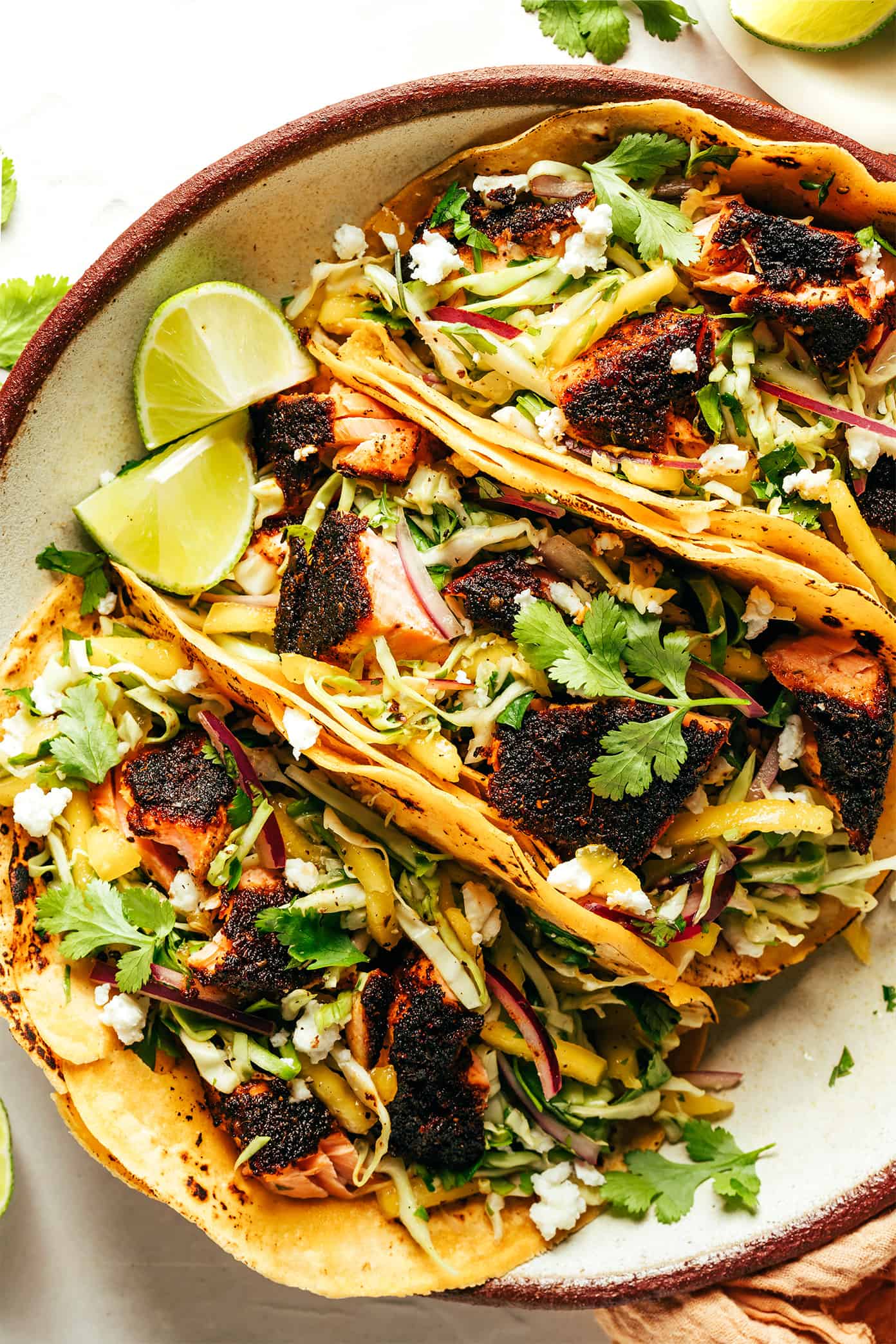 This blackened salmon tacos recipe is layered with a quick mango slaw, corn tortillas, and your choice of zesty toppings. Quick and easy to prepare, naturally gluten-free, and always such a delicious and healthy dinner recipe! | gimmesomeoven.com Blackened Salmon Tacos