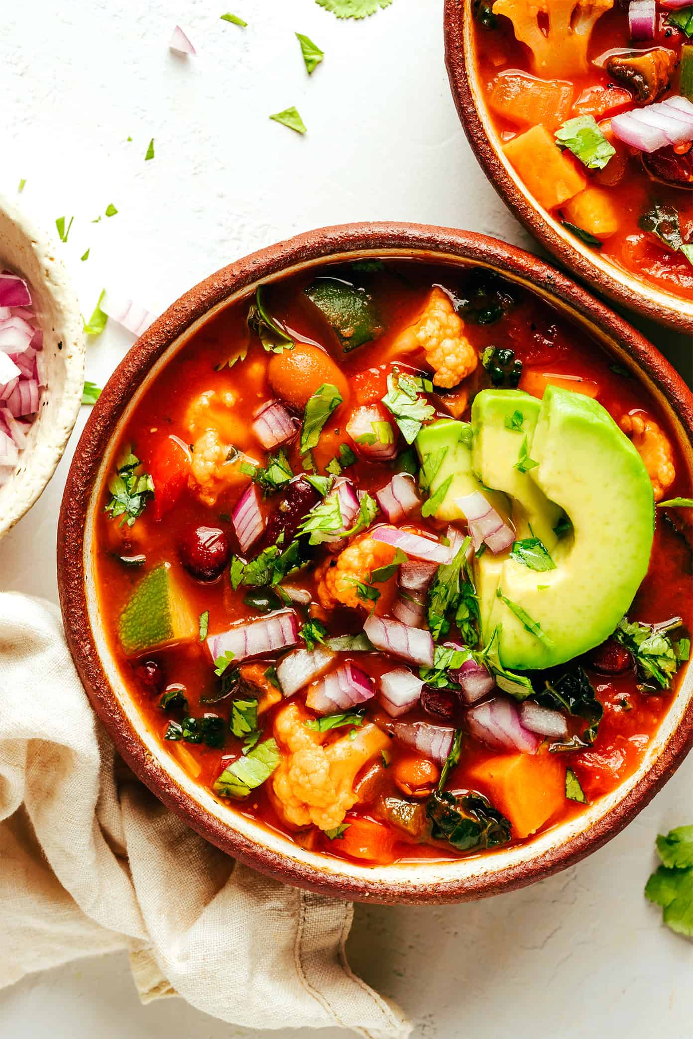 This delicious vegetarian chili recipe is easy to make, full of rich flavor, and loaded up with your choice of beans and veggies (such as sweet potato, bell pepper, zucchini, mushrooms, cauliflower, etc). This soup recipe is naturally gluten-free and vegan, very customizable, and always SO delicious. | gimmesomeoven.com Extra-Veggie Vegetarian Chili with Avocado