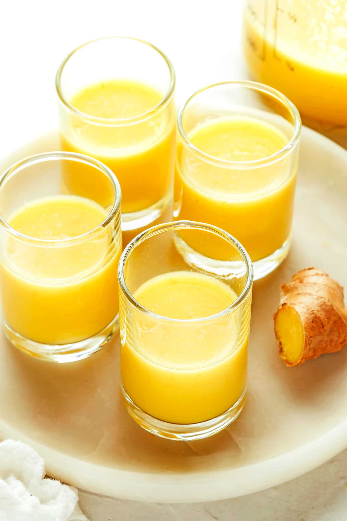 My favorite ginger shot recipe is super easy to make in the blender with 4 ingredients - lemon, orange, coconut water and fresh ginger. Full of healthy anti-inflammatory nutrients, more affordable than the store-bought versions, and easy to customize the flavors to your liking! | gimmesomeoven.com Ginger Shots in Glasses