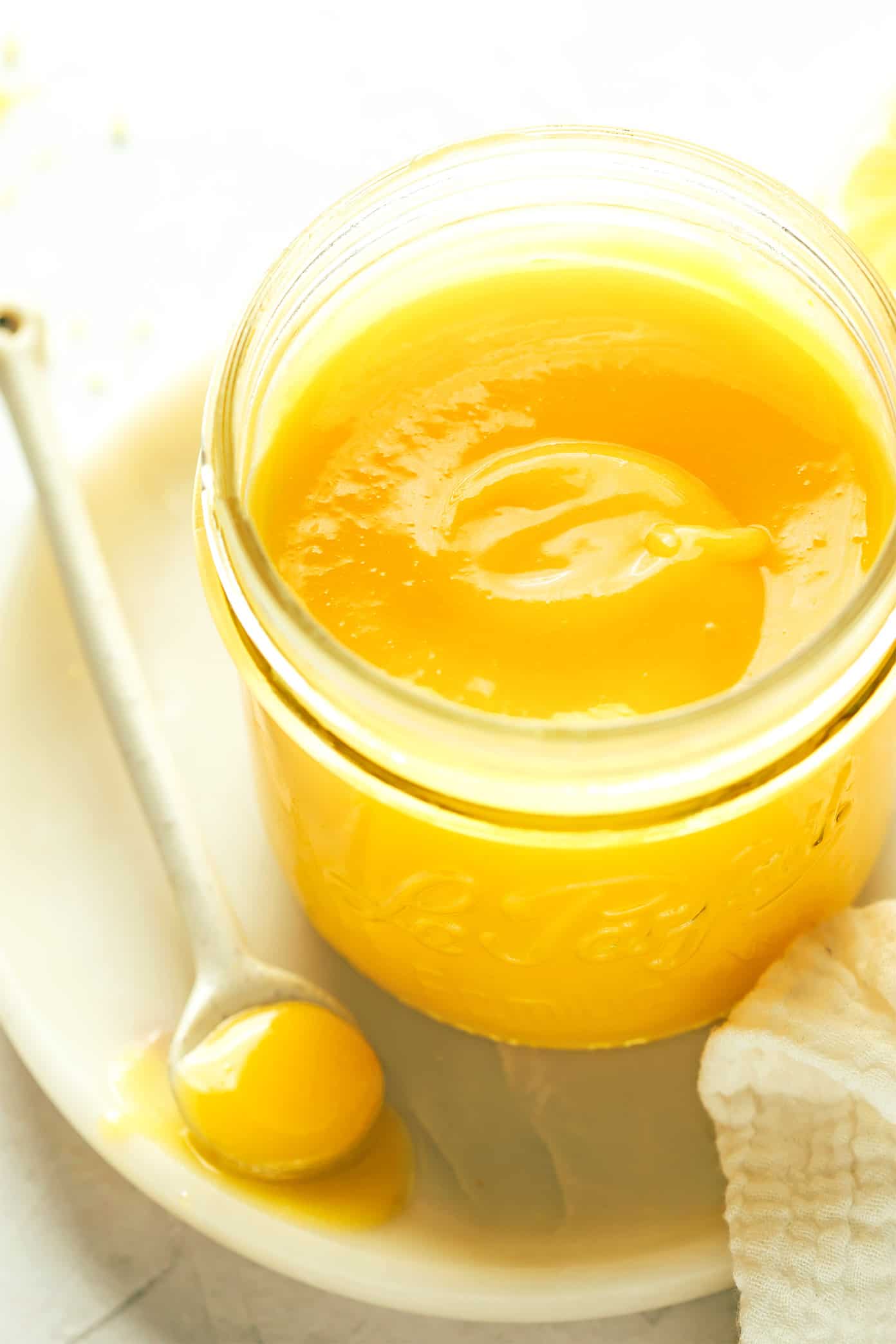 This classic homemade lemon curd recipe is easy to make with 5 ingredients in about 15 minutes. Irresistibly tart, sweet, creamy and delicious, and perfect as a spread or filling for everything from cakes to cookies, crepes, muffins, scones, toast and more. | gimmesomeoven.com Jar of lemon curd with spoon