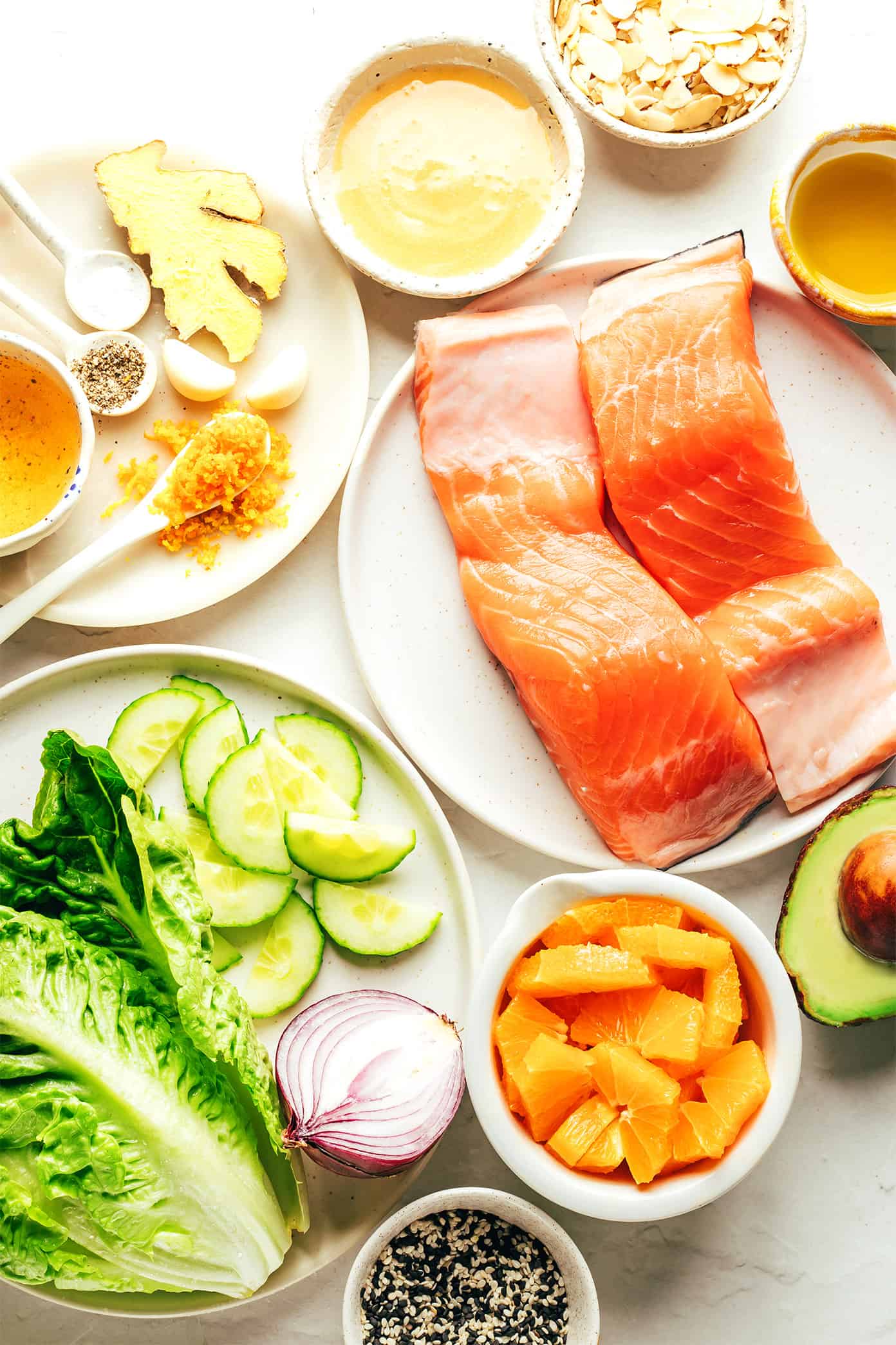 This orange salmon salad recipe is tossed with avocado, cucumber, red onion, toasted almonds, Romaine and drizzled with an irresistible ginger hot honey vinaigrette. It's the perfect sweet and savory entrée salad when you're craving a healthy dinner and it's naturally gluten-free as well. | gimmesomeoven.com Orange salmon salad ingredients