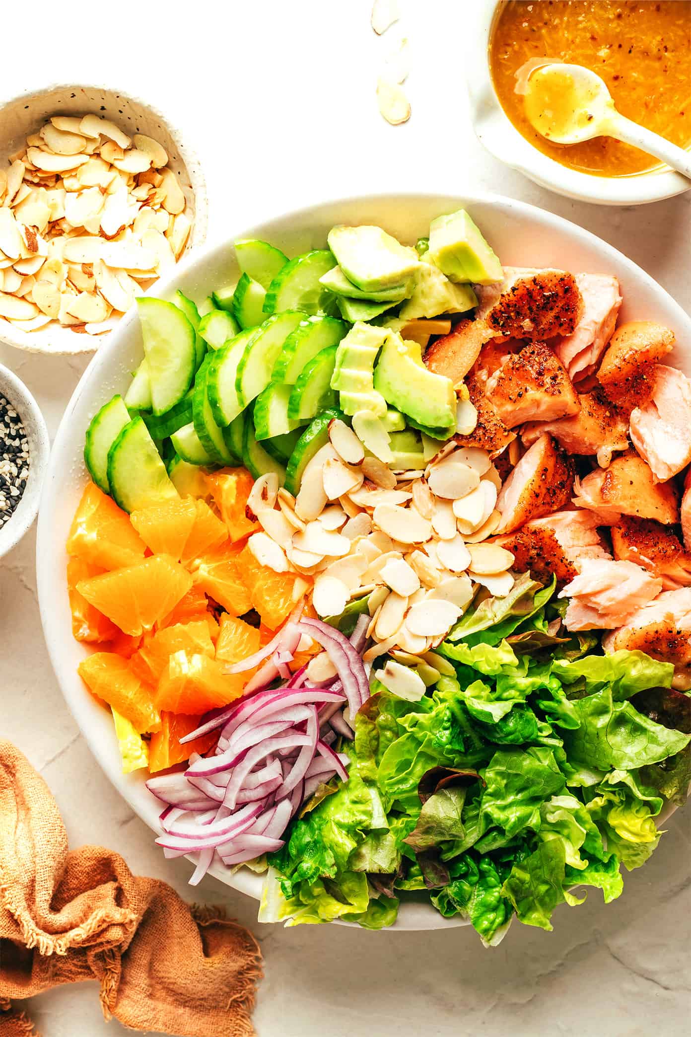 This orange salmon salad recipe is tossed with avocado, cucumber, red onion, toasted almonds, Romaine and drizzled with an irresistible ginger hot honey vinaigrette. It's the perfect sweet and savory entrée salad when you're craving a healthy dinner and it's naturally gluten-free as well. | gimmesomeoven.com Salmon Salad Ingredients prepped in serving bowl