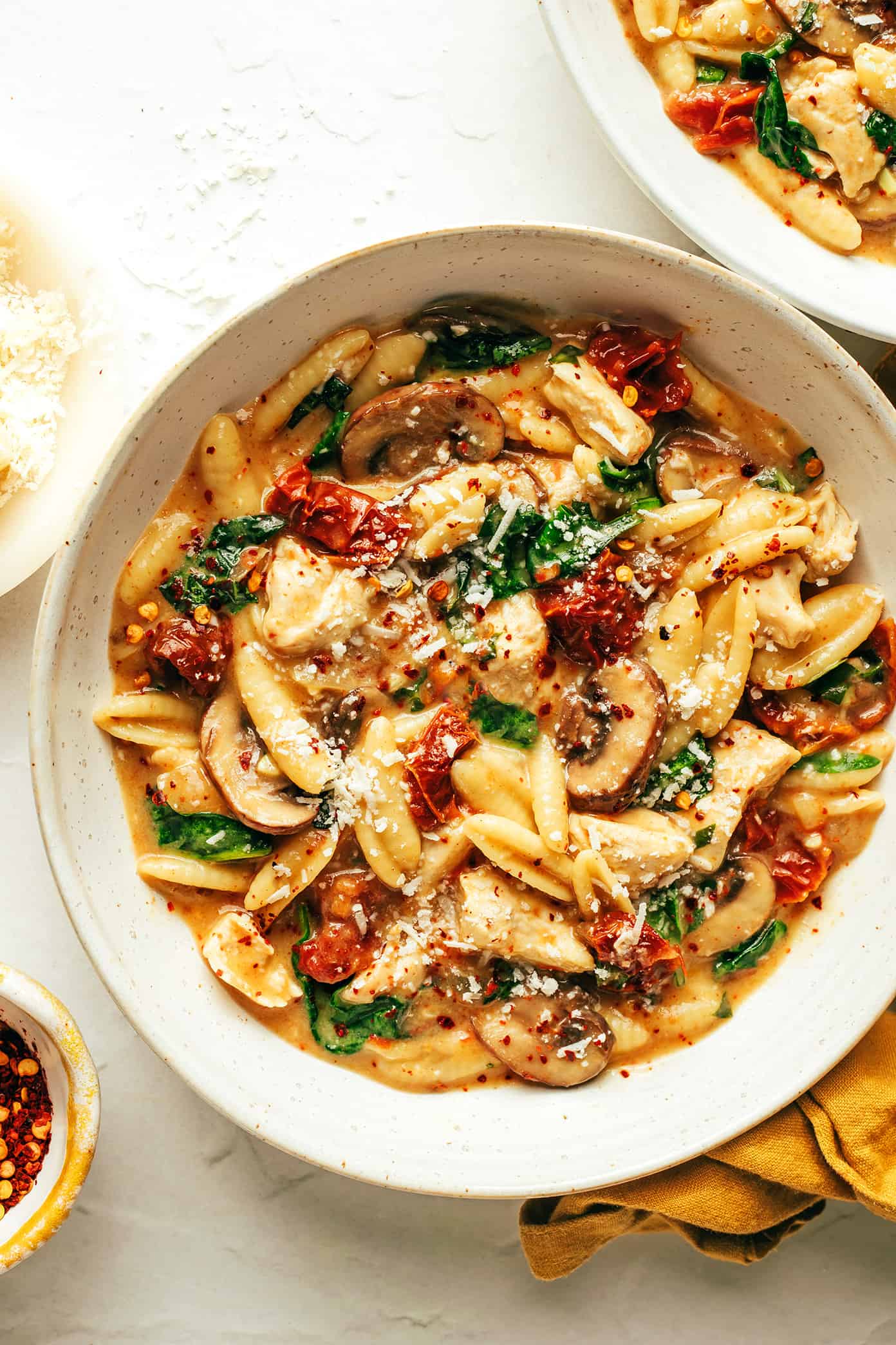 This one pot creamy sun-dried tomato pasta recipe is made with chicken, mushrooms and spinach in a rich garlic basil sauce. Serve topped with lots of Parmesan and enjoy! | gimmesomeoven.com One Pot Creamy Sun-Dried Tomato Pasta in Bowl with Parmesan