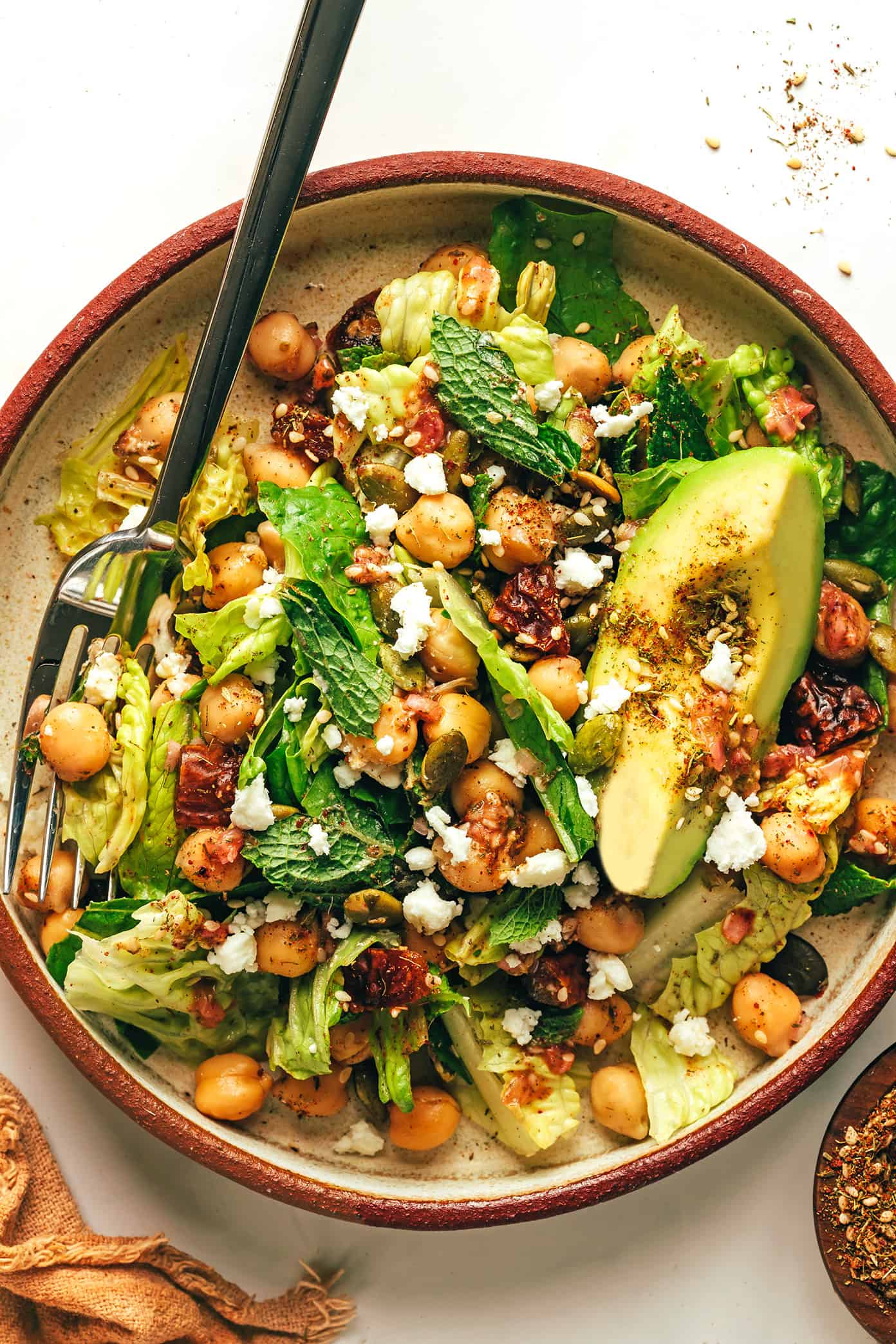 This vibrant green salad is loaded up with chickpeas, Medjool dates, avocado, pepitas, loads of fresh mint, and tossed with a lemony za'atar shallot vinaigrette. It's naturally vegan and gluten-free, but feel free to add a protein such as chicken, steak, shrimp or salmon if you'd like. So fresh and delicious! | gimmesomeoven.com Chickpea avocado and avocado green salad with za'atar vinaigrette in serving bowl with fork