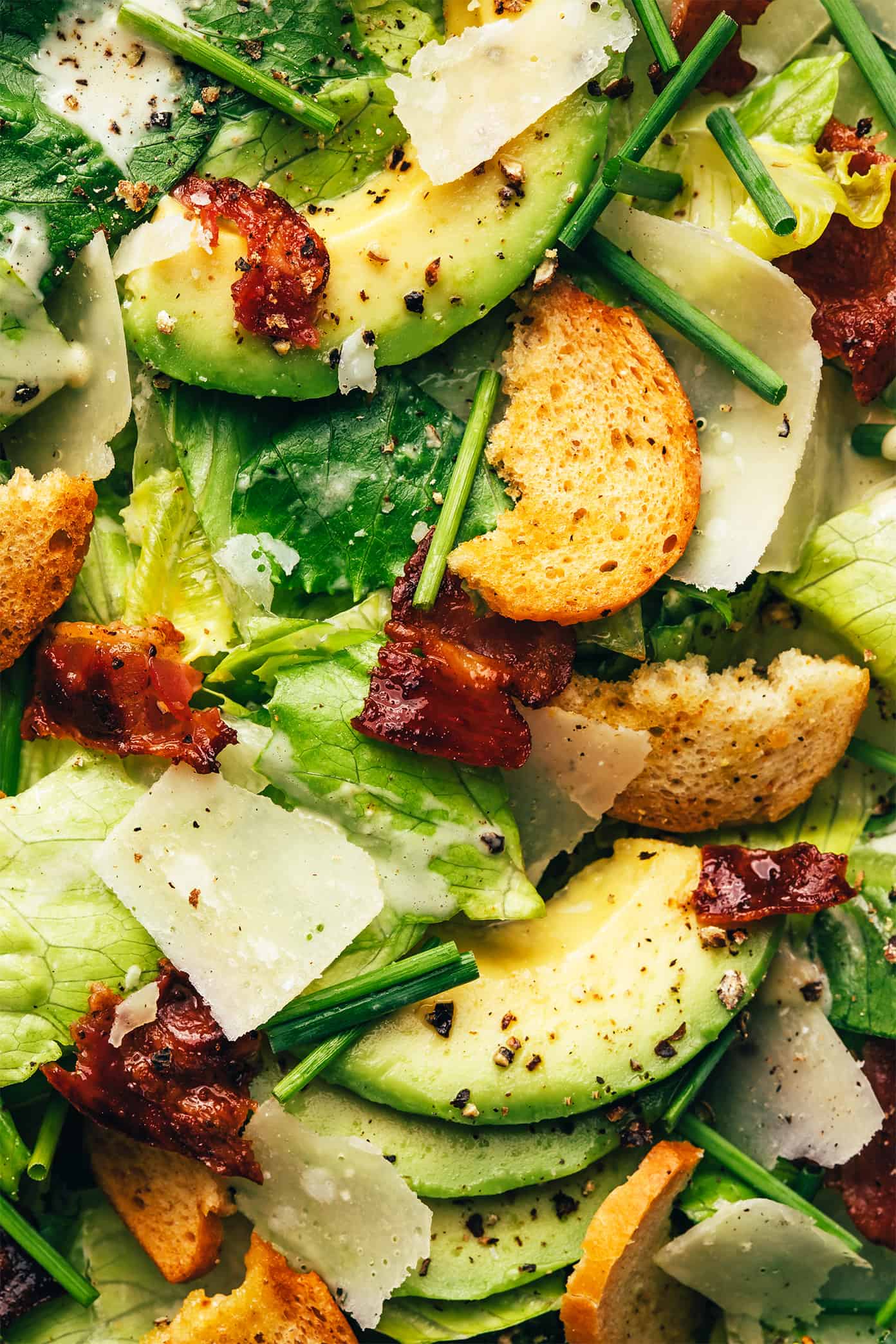 Classic Caesar salad is leveled up with crispy bacon, avocado, rosemary, chives, shaved Parmesan and garlicky croutons. So delicious! | gimmesomeoven.com Bacon Avocado Caesar Salad Closeup