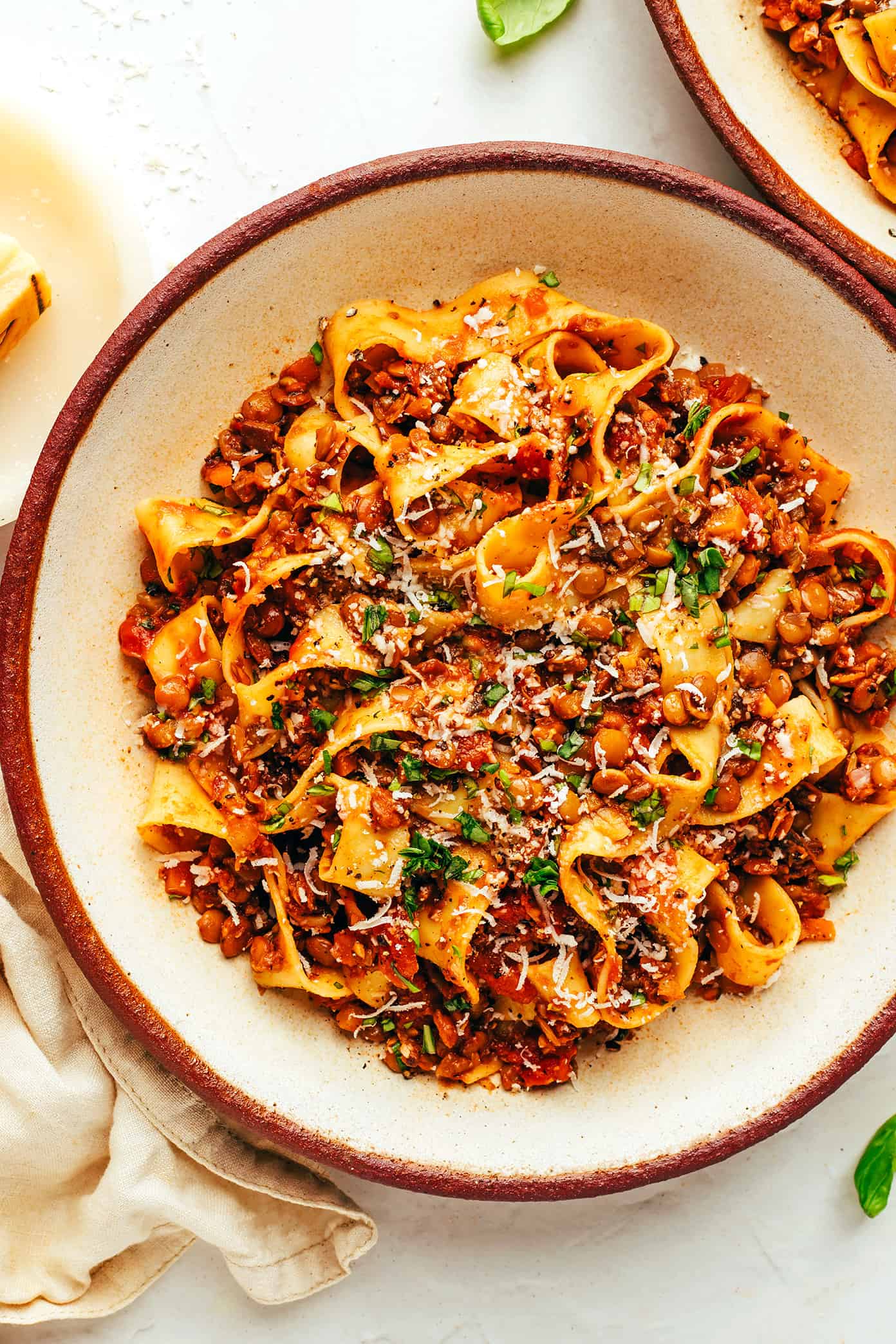 This hearty lentil bolognese recipe is naturally gluten-free, vegetarian and vegan and simmered with a garlicky mushroom-herb tomato sauce. Feel free to serve for dinner with pasta, gnocchi, mashed potatoes, polenta or whatever sounds good! | gimmesomeoven.com Vegetarian bolognese with pasta, parmesan and basil in bowl