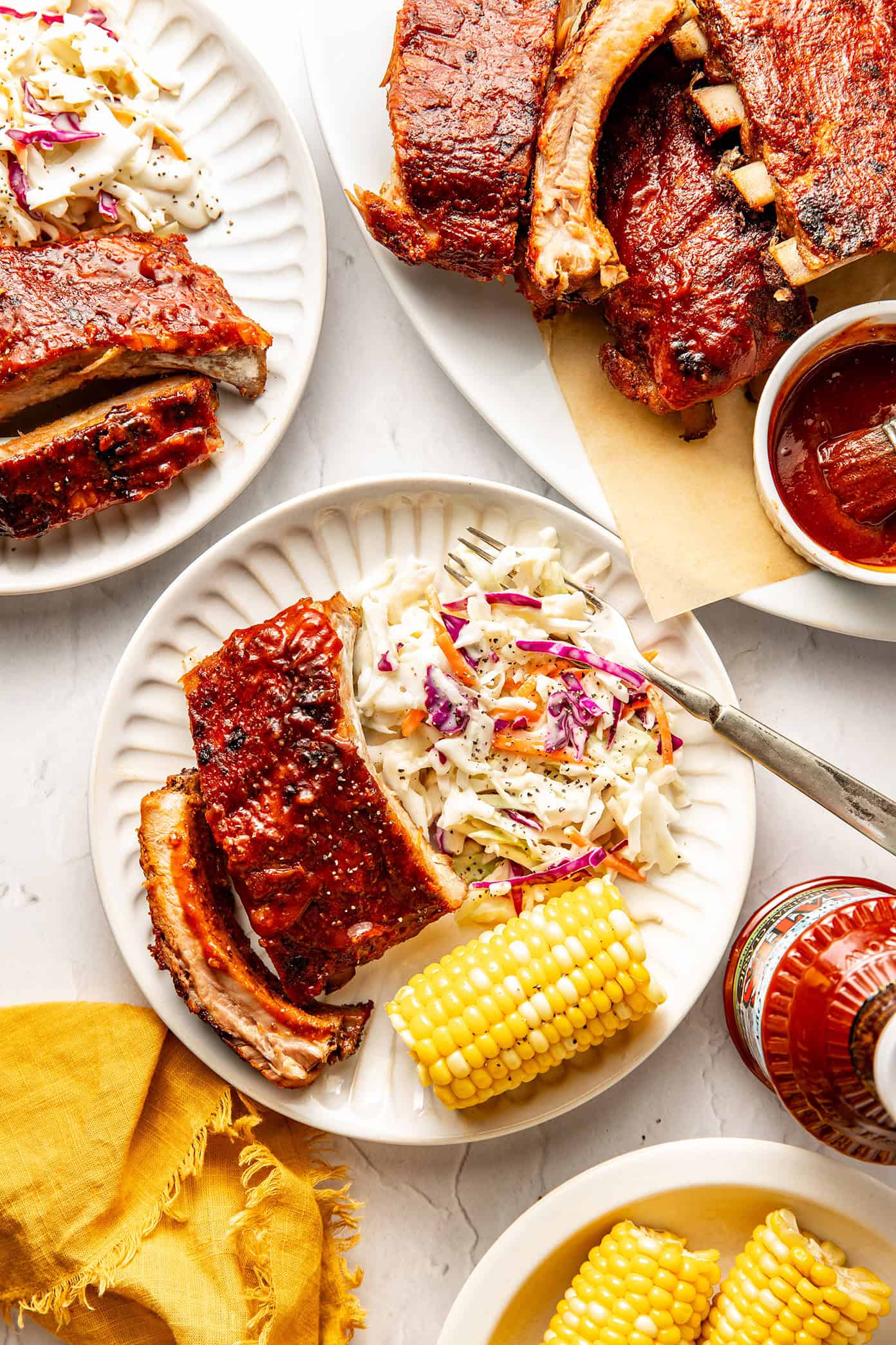 plate of baby back ribs with corn and coleslaw